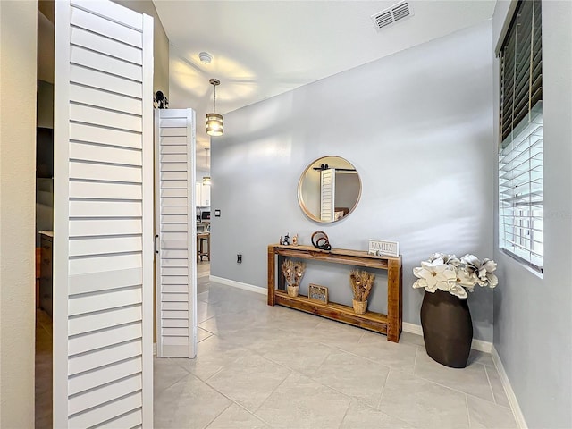 hallway with tile patterned floors, visible vents, and baseboards