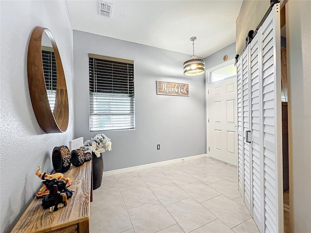 entryway with a wealth of natural light, a barn door, visible vents, and baseboards