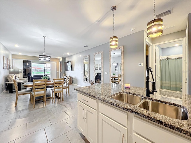 kitchen featuring open floor plan, dark stone counters, a sink, and visible vents