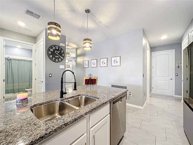 kitchen featuring visible vents, stainless steel dishwasher, white cabinets, a sink, and dark stone counters