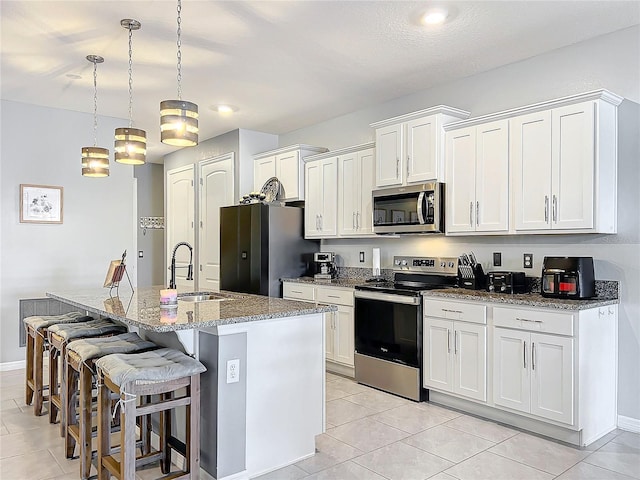 kitchen with an island with sink, appliances with stainless steel finishes, a kitchen bar, a sink, and light tile patterned flooring