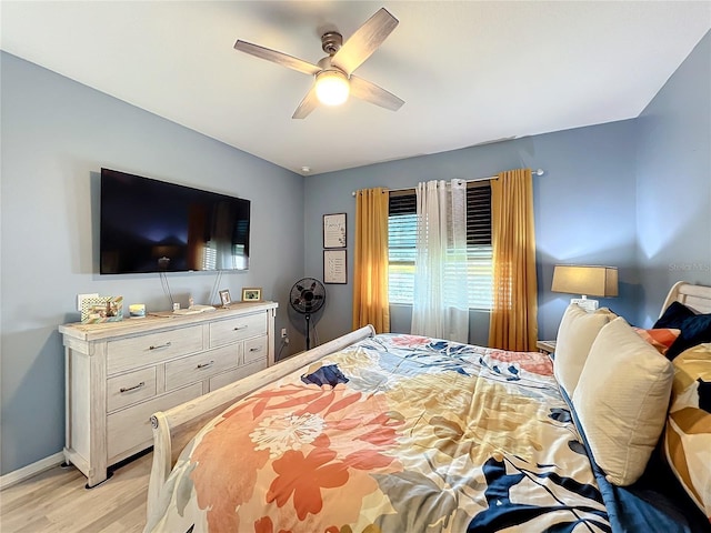 bedroom with a ceiling fan, baseboards, and light wood finished floors