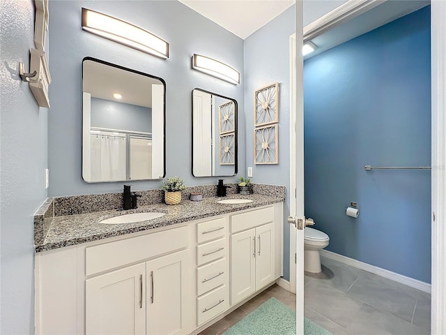 bathroom featuring baseboards, a sink, toilet, and double vanity