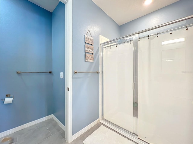 full bath with a shower stall, baseboards, and tile patterned floors