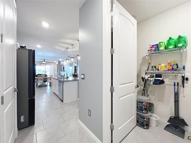 hallway with baseboards, a sink, and light tile patterned flooring