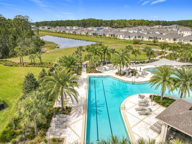 community pool featuring a water view, a yard, a residential view, and a patio