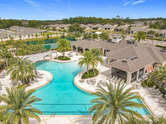 pool with a sunroom, a patio area, and a residential view