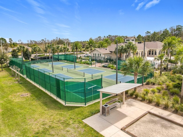 view of tennis court featuring a residential view, fence, and a yard