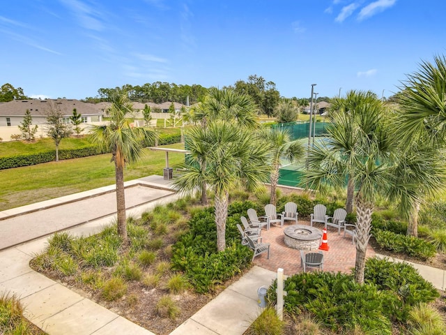 surrounding community featuring an outdoor fire pit, a patio, and a lawn