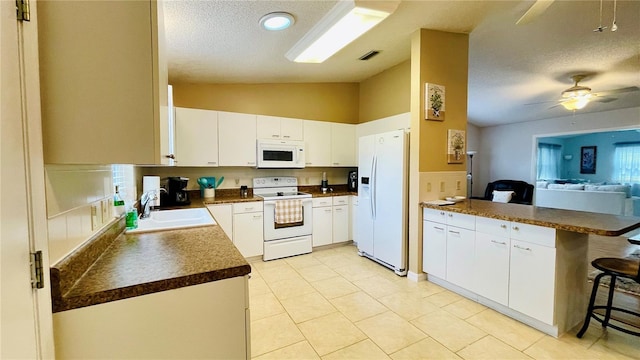 kitchen with white appliances, a breakfast bar, a sink, vaulted ceiling, and dark countertops