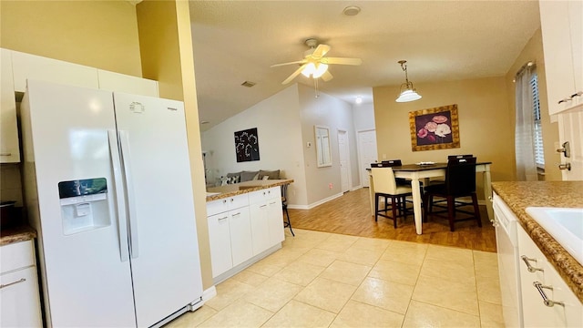 kitchen featuring light tile patterned floors, white refrigerator with ice dispenser, white cabinets, lofted ceiling, and decorative light fixtures