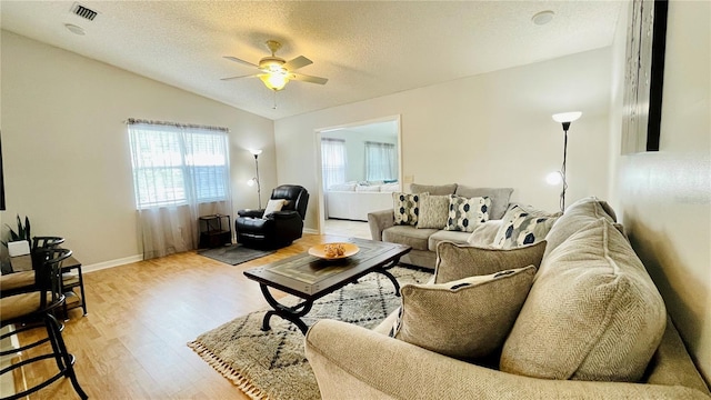 living room featuring visible vents, vaulted ceiling, a textured ceiling, and light wood finished floors