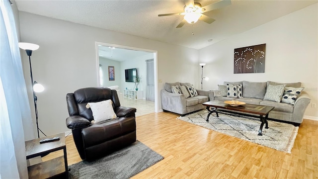 living area featuring lofted ceiling, a textured ceiling, wood finished floors, and a ceiling fan