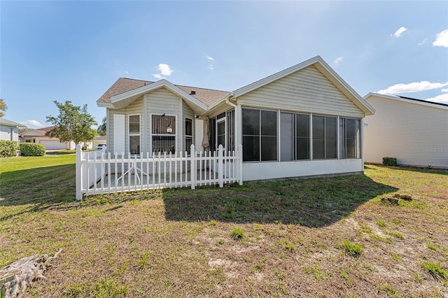 rear view of house featuring a sunroom, a yard, and fence