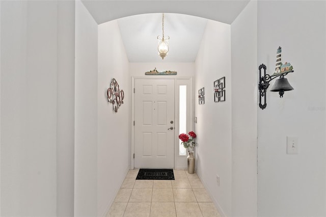 entrance foyer featuring arched walkways, light tile patterned flooring, and baseboards