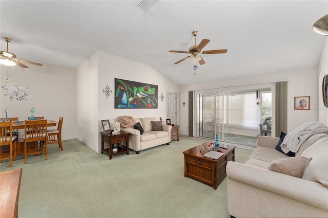 living room with ceiling fan, visible vents, vaulted ceiling, and light colored carpet