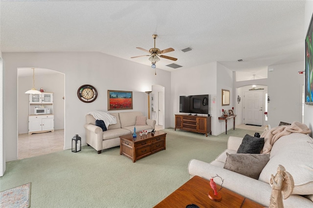 living room featuring lofted ceiling, a textured ceiling, arched walkways, and carpet flooring