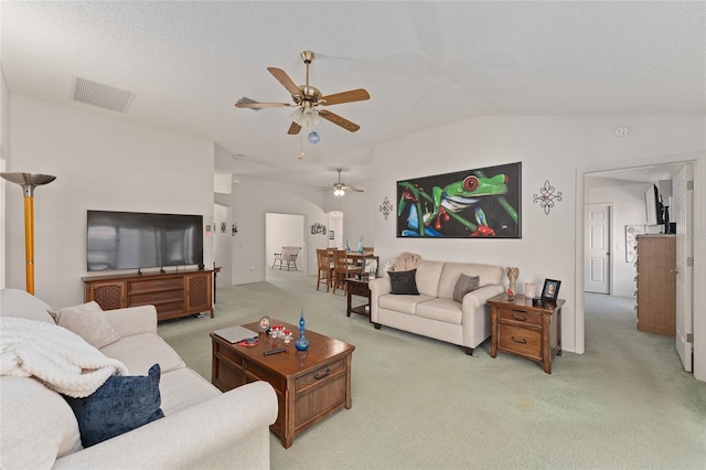 living room featuring lofted ceiling, visible vents, light carpet, and a textured ceiling