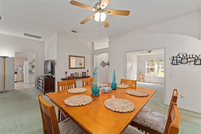 dining room with arched walkways, light colored carpet, a textured ceiling, and baseboards