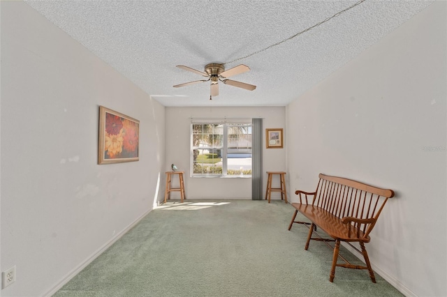 living area with a textured ceiling, carpet floors, a ceiling fan, and baseboards