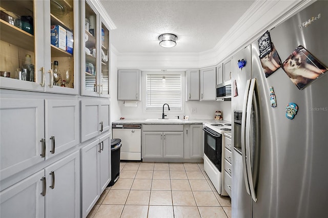 kitchen with light countertops, appliances with stainless steel finishes, light tile patterned flooring, a sink, and a textured ceiling