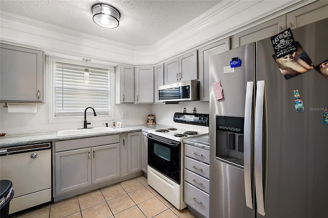 kitchen featuring light tile patterned floors, stainless steel appliances, a sink, light countertops, and gray cabinets