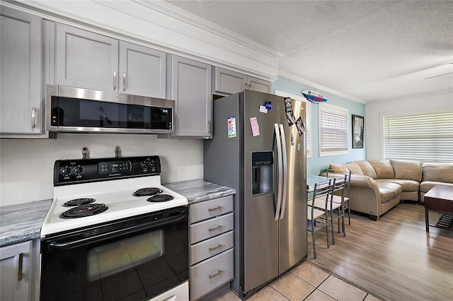 kitchen featuring stainless steel appliances, gray cabinetry, ornamental molding, open floor plan, and a textured ceiling