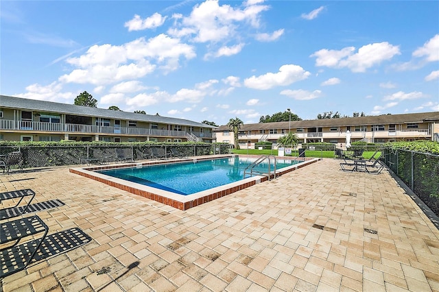 pool featuring a residential view, a patio area, and fence