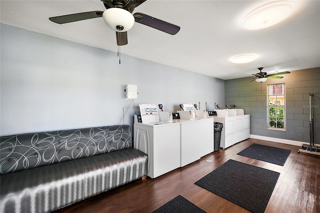 community laundry room featuring concrete block wall, baseboards, washer and clothes dryer, dark wood-style floors, and ceiling fan