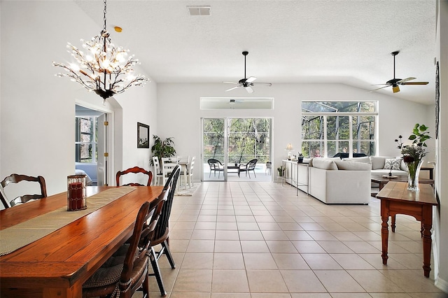 dining space featuring visible vents, light tile patterned flooring, vaulted ceiling, a textured ceiling, and ceiling fan with notable chandelier