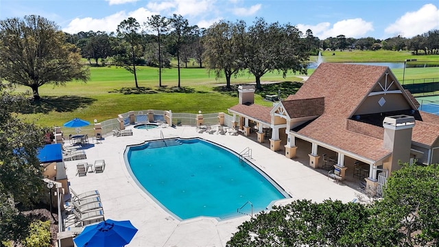 pool with a lawn, a patio, a hot tub, and fence