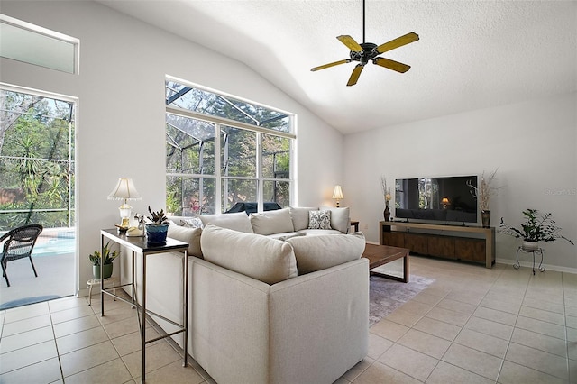 living area featuring vaulted ceiling, ceiling fan, light tile patterned flooring, and a textured ceiling
