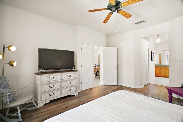 bedroom featuring connected bathroom, visible vents, wood finished floors, and baseboards