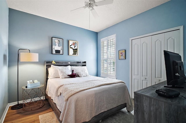 bedroom featuring wood finished floors, a closet, a textured ceiling, baseboards, and ceiling fan