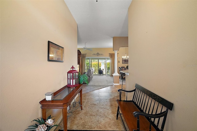 hall with baseboards, an inviting chandelier, light carpet, and ornate columns