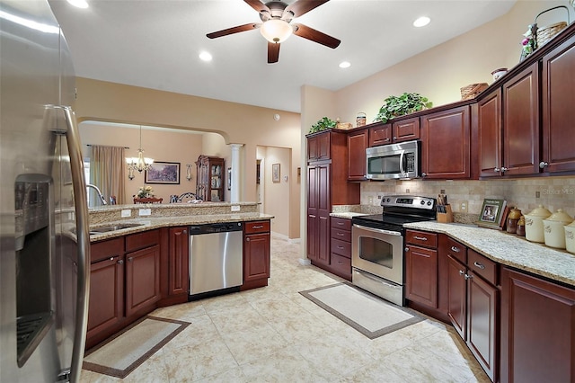 kitchen with appliances with stainless steel finishes, a sink, backsplash, and light stone counters