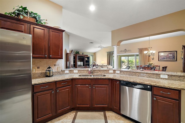 kitchen featuring decorative columns, light stone counters, appliances with stainless steel finishes, a sink, and backsplash