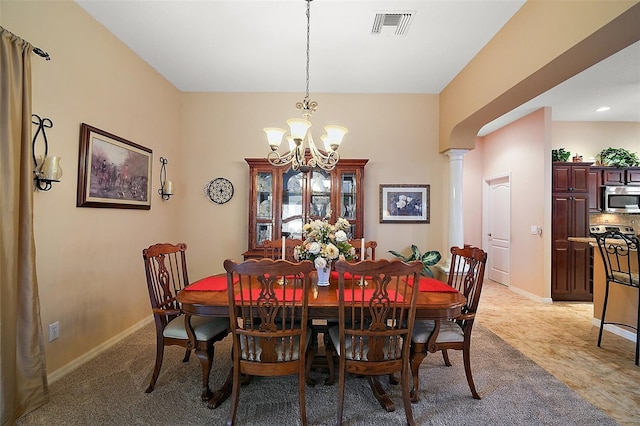 dining area featuring a chandelier, decorative columns, visible vents, and baseboards