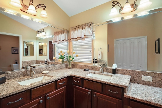 full bathroom with lofted ceiling, a sink, toilet, and double vanity