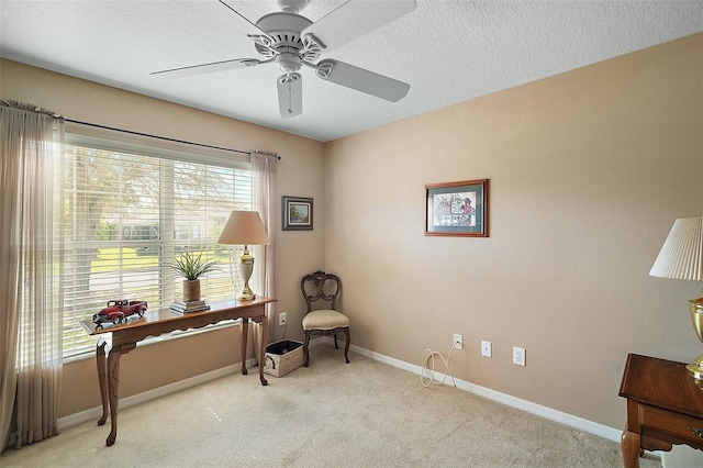 living area with light carpet, ceiling fan, baseboards, and a textured ceiling