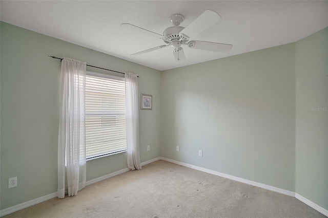 empty room featuring light carpet, a ceiling fan, and baseboards