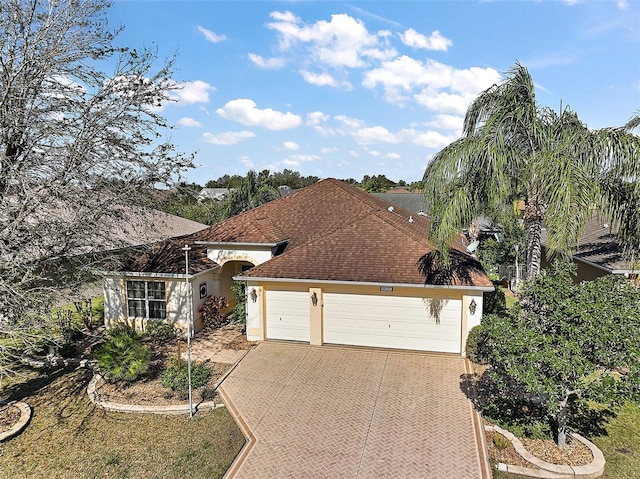 single story home featuring a garage, driveway, a shingled roof, and stucco siding