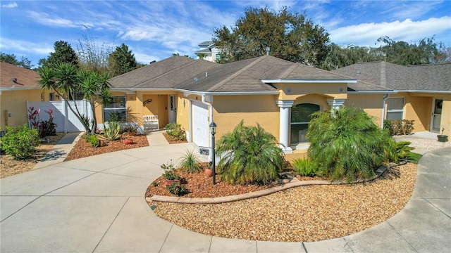 view of front of house featuring a shingled roof, concrete driveway, an attached garage, a gate, and stucco siding