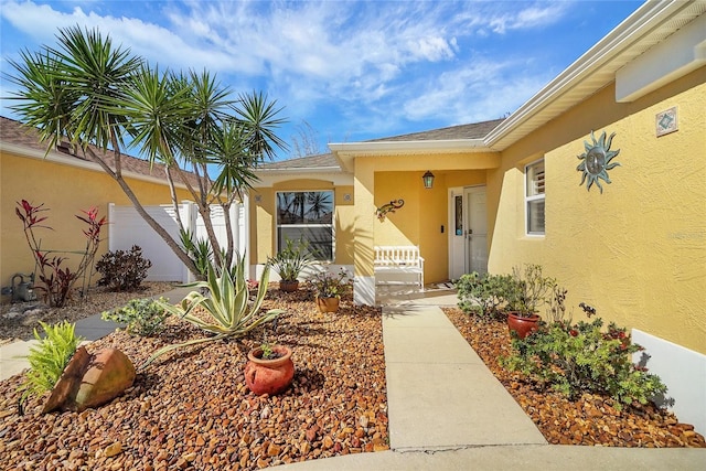 entrance to property with fence and stucco siding