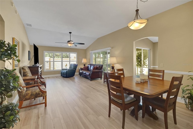 dining area featuring lofted ceiling, light wood finished floors, visible vents, and arched walkways