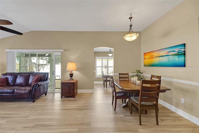 dining area featuring lofted ceiling, light wood-type flooring, arched walkways, and baseboards