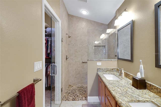 bathroom with double vanity, a spacious closet, walk in shower, and a sink