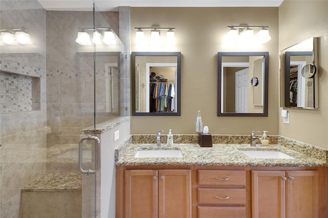 full bathroom featuring double vanity, a spacious closet, a stall shower, and a sink