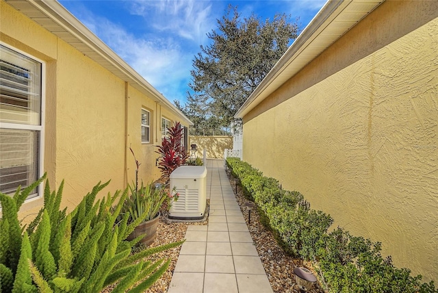 view of side of home with fence and stucco siding