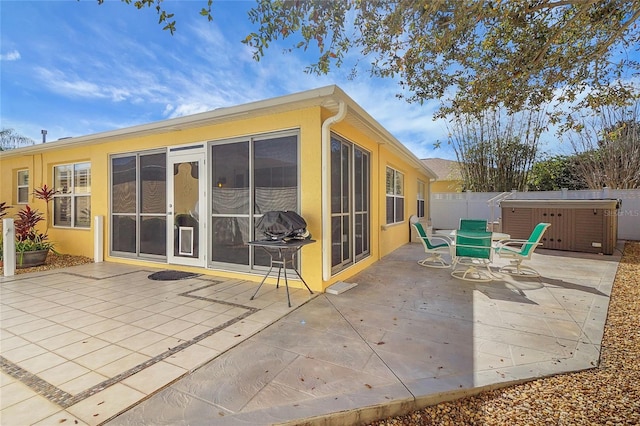 back of house featuring a patio area, a hot tub, fence, and stucco siding